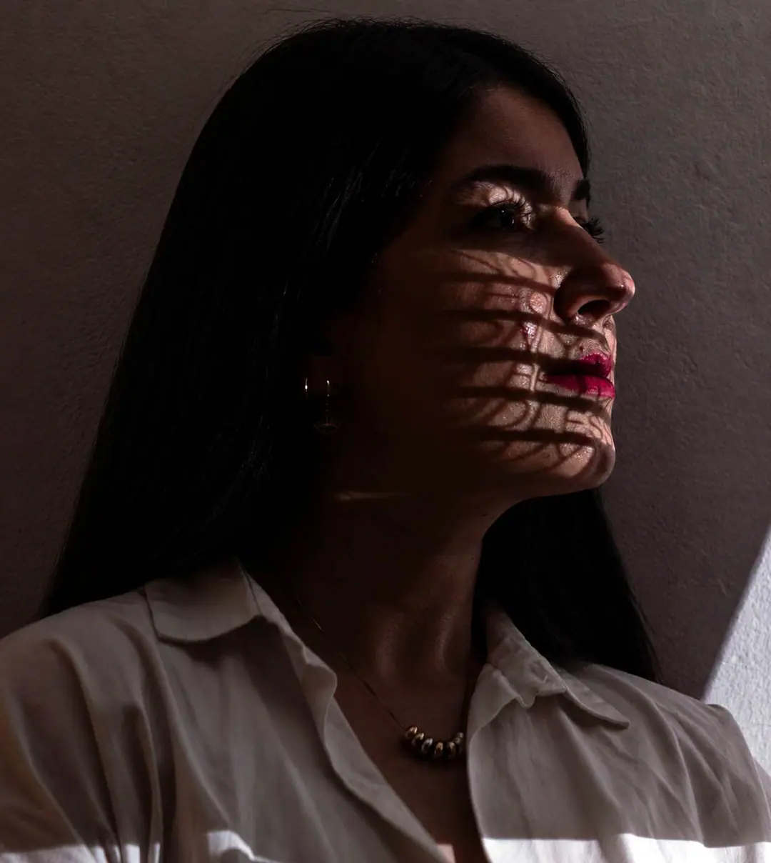 Narges Sedaghat in profile, lit through a pattern of calligraphic shadow