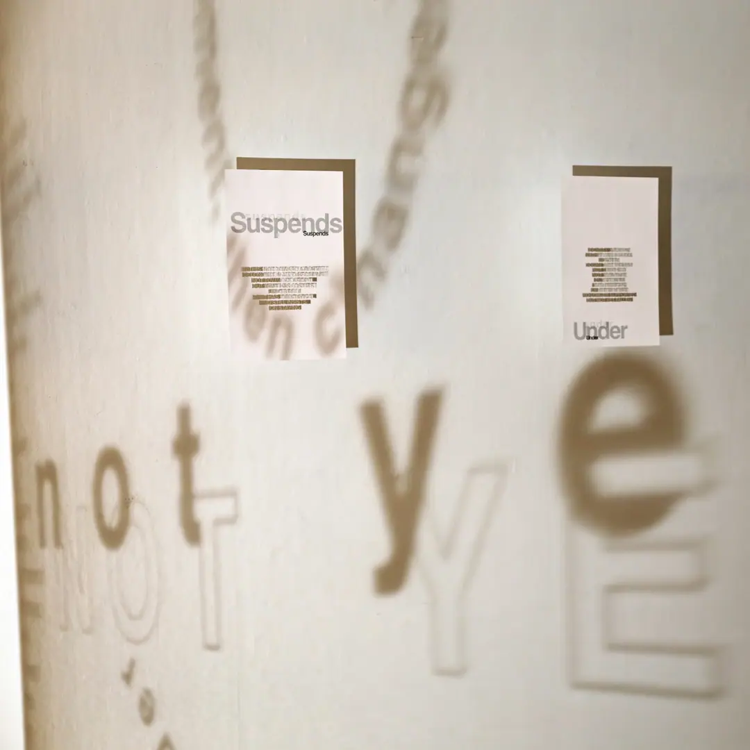 Shadows of the words 'not yet' and Persian calligraphy cast across a gallery wall between hanging text panels