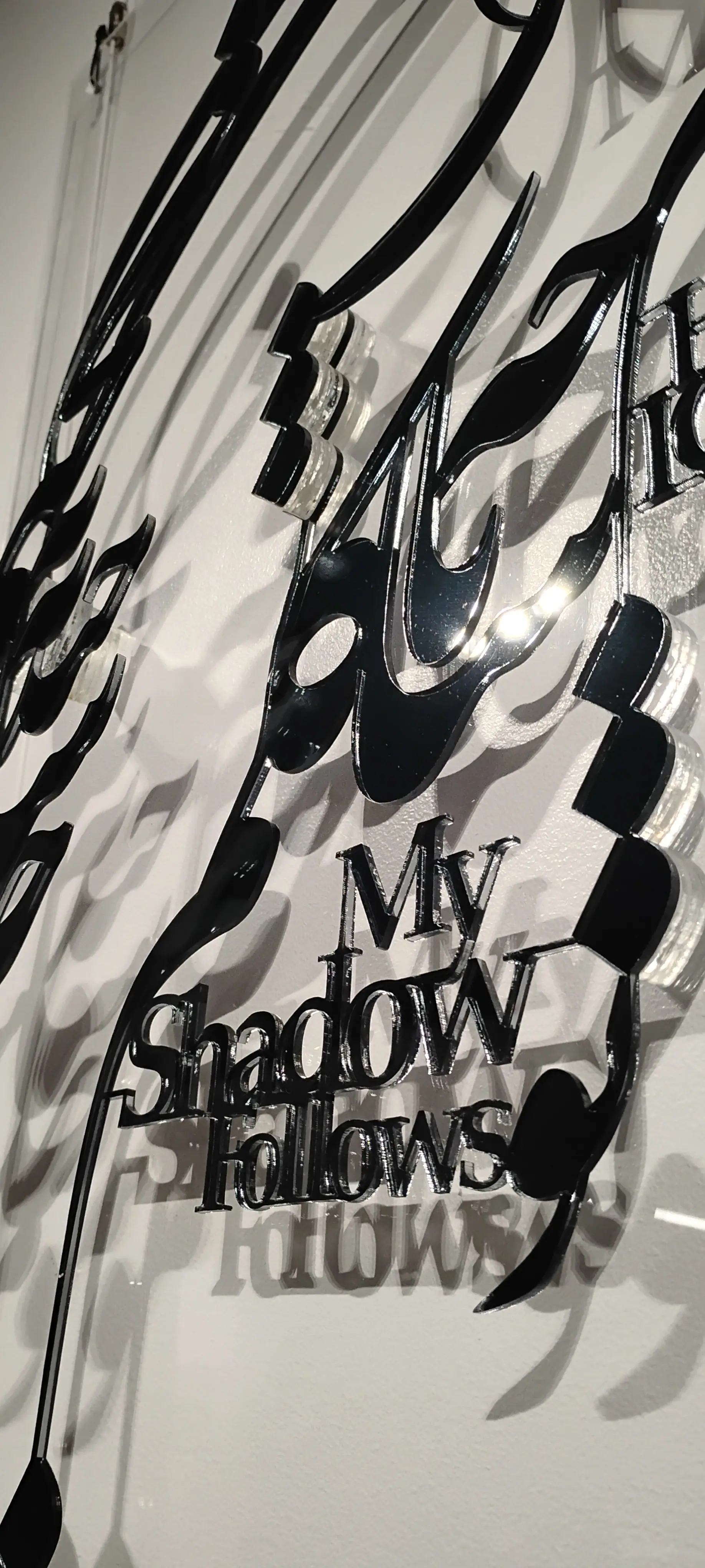 Detail: 'My Shadow Follows' in cut black letters, doubled by its shadow