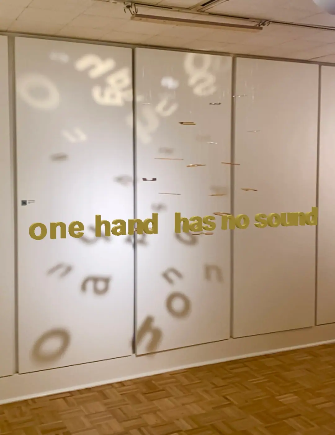 Augmented-reality view: the phrase 'one hand has no sound' appears over the installation