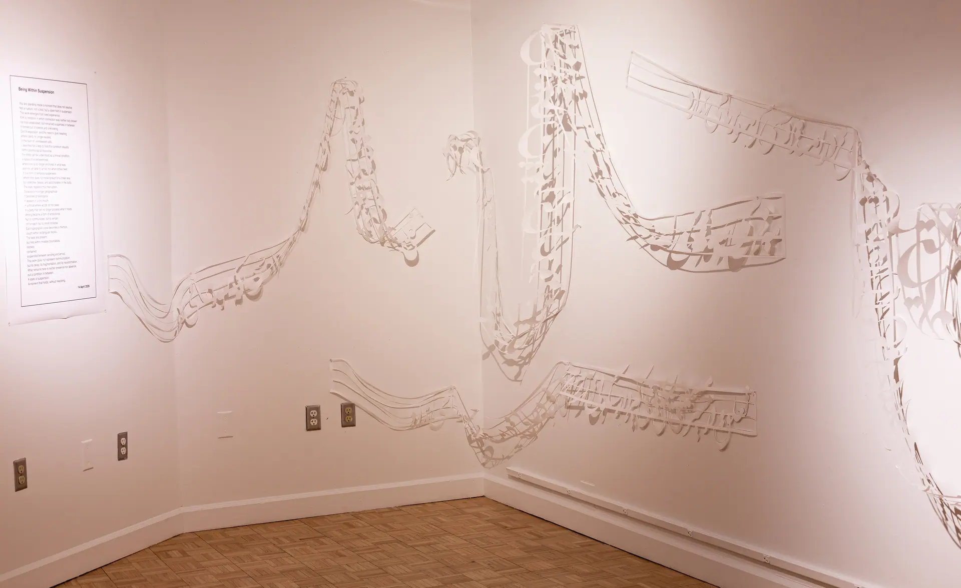 Cut-paper lines of script and musical notation run along two gallery walls